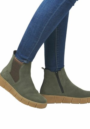 Bottines en suede vertes avec des panneaux latéraux élastiques, comportant une fermeture éclair, une semelle en caoutchouc épaisse et une texture lisse.