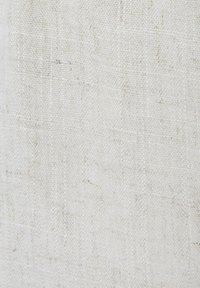 Gros plan sur la texture d'un tissu tissé blanc cassé avec des fils irréguliers créant une apparence légèrement rugueuse, naturelle, de lin.