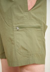 Pantalones cortos de color verde oliva, hechos de tejido ligero, con un bolsillo con cremallera en el lateral y un acabado texturizado con detalles cosidos.