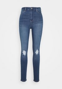 Högmidjade blå skinny jeans med slitna lappar på båda knäna och klassisk femfickorsdesign.