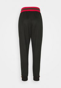 Svarta sweatpants med ett elastiskt midjeband i röd och grön rand. Muddarna är åtsittande; har dekorativa detaljer vid fållen.