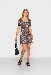 Vestido curto com estampado de leopardo, mangas volumosas, decote quadrado e saia ampla. Sandálias pretas de slide e uma pequena bolsa preta.