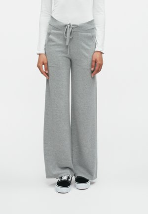 Harmaat leveät collegehousut, jotka on valmistettu pehmeästä kankaasta. Niissä on joustava vyötärö, jossa on naru, sekä kaksi sivutaskua.