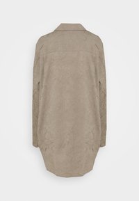 Camicia a maniche lunghe in tessuto beige stropicciato, con colletto classico e orlo dritto con lati arrotondati. Design semplice e texturizzato.