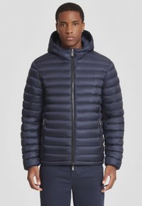 Giacca puffer blu navy con cappuccio, caratterizzata da un motivo trapuntato, zip frontale e tasche laterali. Tessuto morbido con un design slim fit.