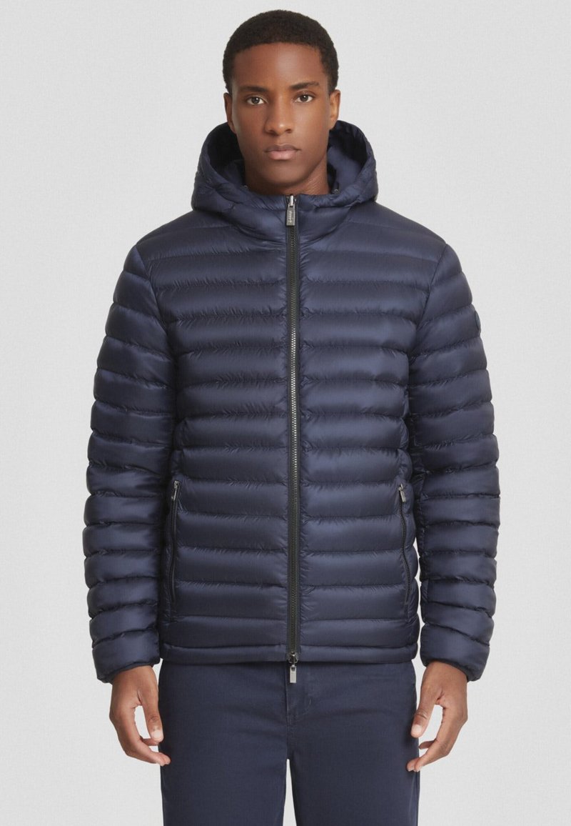 Giacca puffer blu navy con cappuccio, caratterizzata da un motivo trapuntato, zip frontale e tasche laterali. Tessuto morbido con un design slim fit.