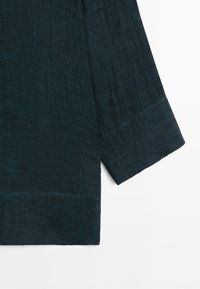 Dark blue textured fabric sleeve with a wide cuff, shown against a white background.