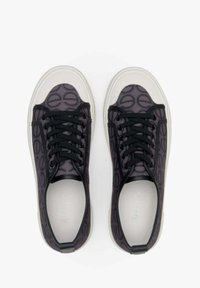 Zwarte en grijze sneakers met een patroon van ronde vormen, vetersluiting aan de voorkant en een witte rubberen zool; gladde textuur met een contrasterende neuskap.