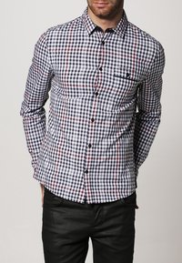 Herenoverhemd met ruitpatroon in marineblauw, wit en rood. Voorzien van knoopsluiting, kraag en een enkele borstzak. Gemaakt van een katoenmix.
