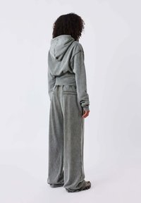 Grijze hoodie trainingsanzug van zacht materiaal; heeft een relaxte pasvorm met wijde broekspijpen en een cropped hoodie, met een subtiele glans.