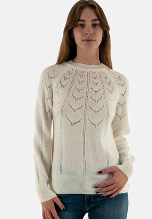 Maglione lavorato a maglia crema con scollo rotondo, caratterizzato da un motivo a foglia, polsini e orlo a coste, e una texture morbida. Abbinato a jeans.