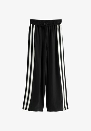 Pantaloni negri cu croială largă și talie elastică, având două dungi albe verticale pe fiecare parte. Confecționați dintr-un material moale și ușor.