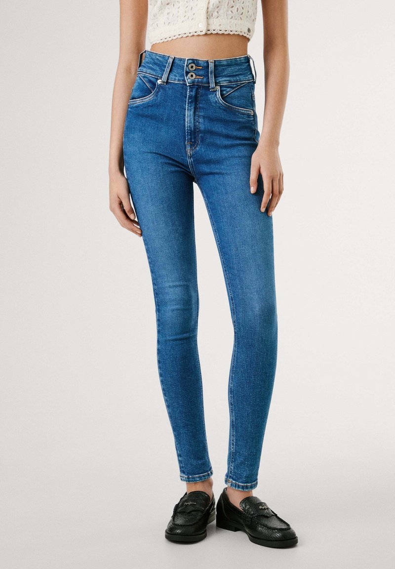 Plave skinny traperice visokog struka s glatkom teksturom trapera, koje imaju dva prednja džepa i dvostruko kopčanje na struku.