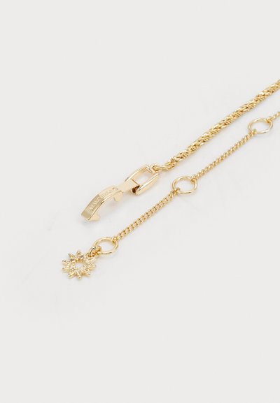 Aukso spalvos kaklo grandinėlė su pintu dizainu, kurioje yra krabų užsegimas ir saulės formos pakabukas.