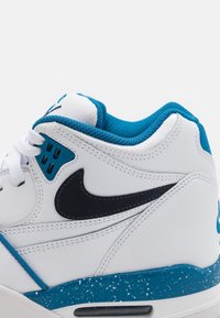 Bílé a modré Nike tenisky s černým swushem, bílými šňůrkami, polstrovaným límcem a skvrnitou modrou mezipodešví.