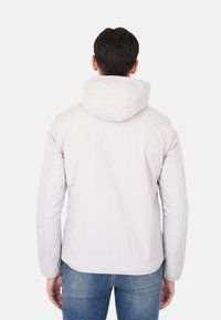 Giacca grigia chiara con cappuccio, caratterizzata da una texture liscia e cuciture a vista, progettata con una silhouette aderente e polsini elasticizzati.