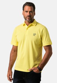 Gul polo shirt lavet af bomuld med en kort krave, der har et mørkt logo "JP 1880" på venstre side. Casual fit med korte ærmer.