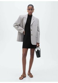 Gray oversized blazer with two buttons, black fitted dress, brown flat sandals, and small black handbag; smooth textures and simple design.