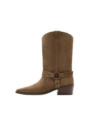 Bota cowboy de ante marrón hasta media pantorrilla con punta afilada, correa decorativa y anilla metálica, y tacón bajo apilado.