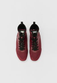 Scarpe sportive rosse alte con pannelli in rete, lacci neri e una suola in gomma texturizzata. Include un tab per il tallone per un facile indossamento.
