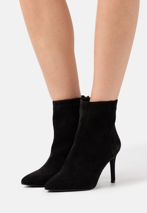 Schwarze Wildleder-Stiefeletten mit spitzer Zehe und hohem Stiletto-Absatz, die eine glatte Textur und ein minimalistisches Design aufweisen.