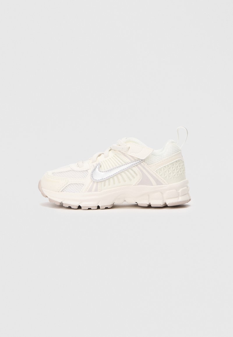 Sapatilhas de tom bege claro com parte superior em rede, detalhes texturizados e o swoosh da Nike em branco. Possui bico arredondado e sola almofadada para conforto.