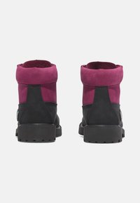 Botas de ante negras y ciruela con un cuello doblado, acentos texturizados en negro y una suela gruesa. Presenta un detalle de hardware en el lateral.