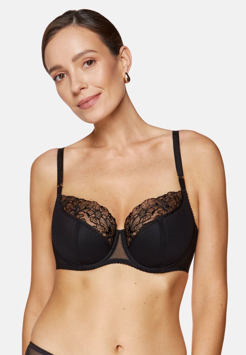 Czarny biustonosz z przejrzystymi miseczkami, koronkowymi detalami, regulowanymi ramiączkami i gładkim pasem pod biustem. Kwiatowy wzór na koronce dodaje tekstury i detali.