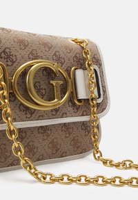 Ruskea tekstiilinen olkalaukku kultaisen ketjun kanssa, kohokuvioitu logokuvio ja särmikäs kultainen logolukko. Sileät nahkakoristeet.