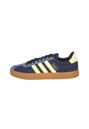 Zapatilla deportiva azul marino con rayas y acentos amarillos. Presenta una puntera de ante, parte superior de textil y suela de goma. Diseño con cordones.