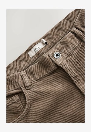 Brune kordfløjlsbukser med metalknap og label til at læse "NEXT Straight Fit" inde i taljen.