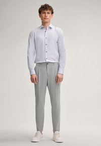 Chemise à motifs bleu clair avec un col boutonné, assortie à un pantalon gris clair et des baskets blanches. Devant plat et coupe ajustée.