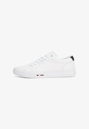 Sneaker bianco realizzato in materiale liscio con punta rotonda, suola bianca piatta, design di allacciatura a fantasia e un piccolo accento nero, rosso e bianco sul lato.