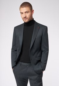 Szary dopasowany �żakiet z klapami, w połączeniu z czarnym golfem. Posiada czerwoną emblemat na klapie, dopasowane spodnie.