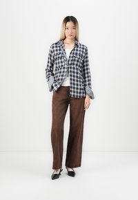 Blue and white checkered shirt with contrasting check cuffs, paired with brown wide-leg pants and black pointed-toe shoes.
