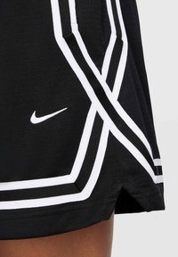 Black athletic skirt featuring white striped accents, a Nike logo, and contrasting trim, with a soft texture and flared design.