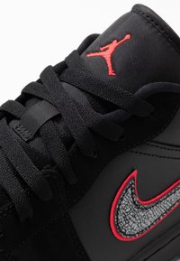 Baskets noires avec cuir texturé et panneaux en mesh. Dotées d'un logo brodé rouge et d'un swoosh à motif gris. Conception à lacets.