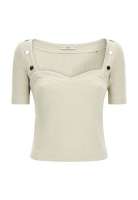 Top corto de manga corta ribeteado en beige claro con escote en forma de corazón y detalles de botones metálicos en las tirantes, etiquetado GUESS en el interior del cuello.