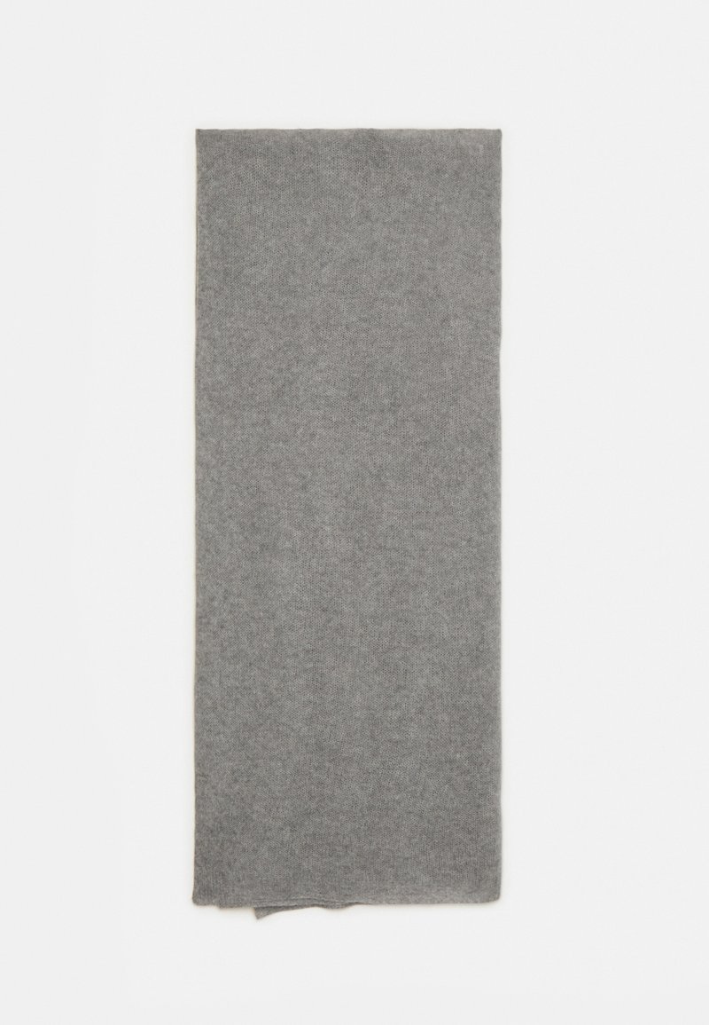 Écharpe en laine grise, forme rectangulaire, texture douce et design simple. Les bords sont légèrement effilochés pour un look décontracté.