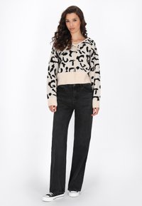 Pulover scurt bej cu imprimeu leopard negru, având un guler cu șnur. Asortat cu blugi negri cu talie înaltă, drepti, și adidași.