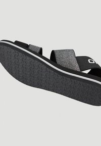 Mustat ja harmaat liukusandaalit, joissa on kaksi leveää hihnaa. Rakeinen pohja ja kuosillinen kumipohja, jossa on kontrastiväri valkoinen reuna.