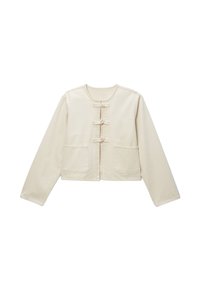 Veste cropped beige clair en tissu à texture lisse, dotée de trois fermetures à bouton et de deux poches avant.