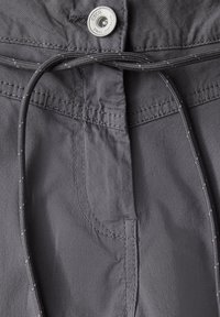 Pantalones cortos de tela gris con cintura ajustable mediante cordón, botón plateado y detalles de costura visibles. Textura suave sin patrones visibles.