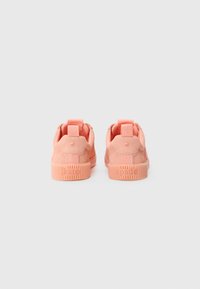 Pink suede sneakers with a textured rubber sole. Features a pull tab at the back and embossed brand name on the sole.