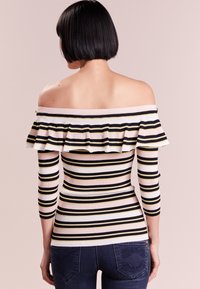 Off-the-shoulder striped top featuring black, white, and yellow stripes, ribbed texture, and a ruffled neckline with three-quarter sleeves.