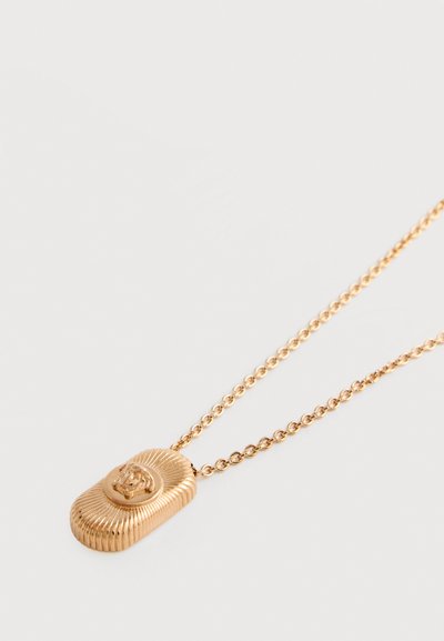 Κολιέ σε χρυσό τόνο με μενταγιόν σε σχήμα οβάλ, διακοσμημένο με λεπτομερή κεφαλή λιονταριού, κρεμασμένο από μια λεπτή αλυσίδα.