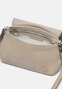 Borsa a tracolla in pelle beige con chiusura a zip, tasca interna e dettagli della base circolare. Texture liscia e design minimalista.