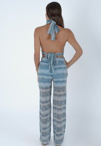 Pantaloni con motivo zigzag blu e grigio, dotati di scollatura all'americana e dettaglio con laccio sulla schiena. Il tessuto sembra leggero e ha una texture setosa.