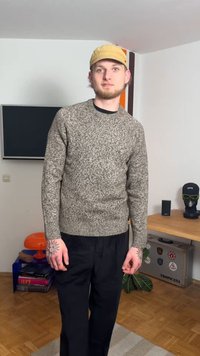 Pull en tricot gris-brun avec un motif texturé, col rond et manches longues, associé à un pantalon large noir.