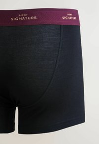 Tumesinised bokserid, valmistatud pehmest kangast. Omavad burgundi värvi elastset vööd, millel kuldsed tähed "NEXT SIGNATURE". Õmblusteta disain.